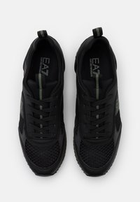 Černé tenisky s mřížkovými panely, texturovanými povrchy, tonalními tkaničkami, zelenými akcenty a poutkem. Obsahují logo na stélce.