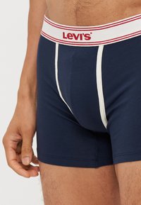 Námornícky modré boxerky vyrobené z bavlny, s bielym pásom so žiadaným logom "Levi's" v červenej farbe a bielymi akcentmi vpredu.