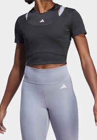 Svart kortärmad croptop med smal passform och rund halsringning. Kombinerad med ljusgrå högmidjade leggings som har en vit logotypdetalj.