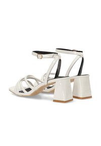 Sandalias blancas de charol con punta cuadrada, múltiples correas, correa ajustable en el tobillo y tacón ancho con base de aspecto madera.