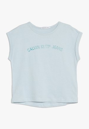 Jasnoniebieski krótki T-shirt z krótkim rękawem, z wyhaftowanym na przodzie napisem "CALVIN KLEIN JEANS" w zaokrąglonych turkusowych literach.
