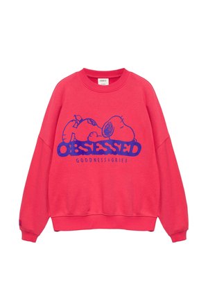 Sweat-shirt rouge avec un motif bleu d’un Snoopy endormi au-dessus du mot « OBSESSED » et un petit texte « GOODNESS & GRIEF » en dessous.
