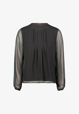 Blouse noire avec de longues manches transparentes, un devant plissé, un col rond et une texture lisse. Les sections transparentes offrent un contraste avec le corps opaque.