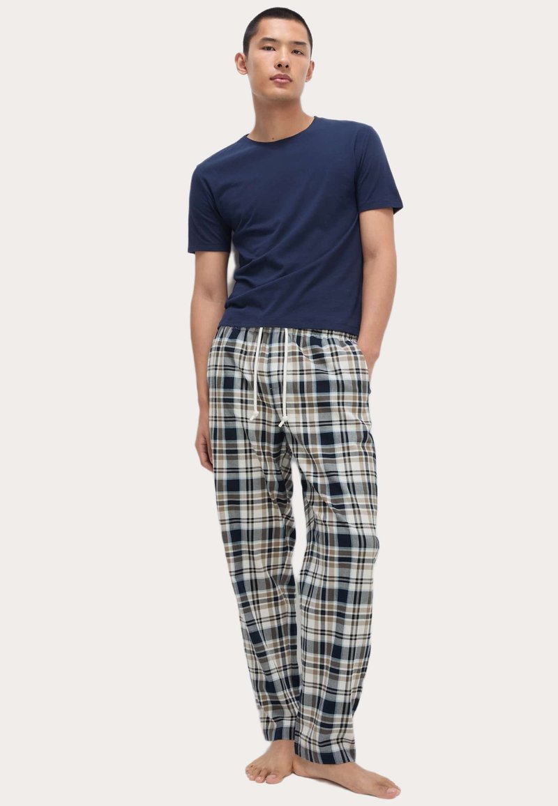 Mørkeblå bomulds t-shirt i kombination med plaid flannel pyjamas i blå, beige og brun. Pyjamaserne har en elastisk talje med snoretræk.