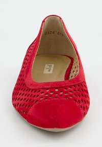 Czerwony but z gładkim czubkiem i perforowaną cholewką. Płaski fason wykonany z miękkiego zamszu, o zaokrąglonym kształcie i beżowej wyściółce wewnętrznej.