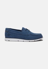 Mocassin décontracté bleu marine avec semelle blanche, laçage sur le devant et logo Timberland embossé près du talon.
