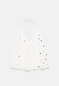 Top dos nu blanc avec sequins argentés, décolleté en V profond et fines bretelles nouées au niveau du cou, présenté sur un fond clair.