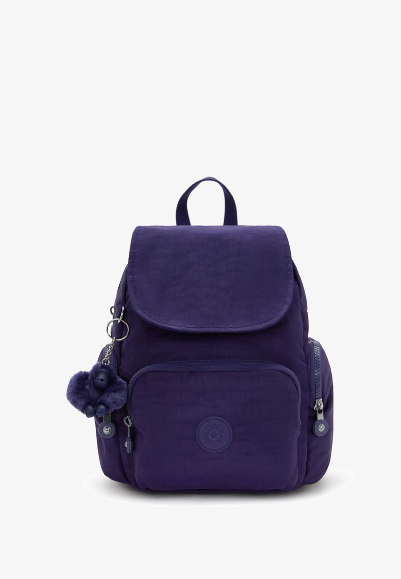 Reppu purppurainen, kompakti muotoilu etupuolella vetoketjullinen tasku, sivussa vetoketjullinen tasku, päällä kansi ja pieni pehmolelu avaimenperä kiinnitettynä sivulle.
