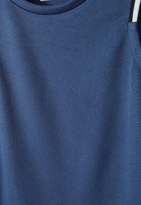 Sinine, tekstuuriga sportlik tank top, mis on valmistatud hingavast materjalist ja millel on ümar kaelus. Küljel kontrastsetes värvides aktsendid.