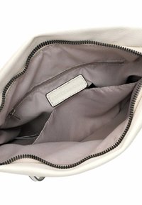 Indvendig i en lys beige taske med en glat læderoverflade, en lynlåslukning og et blødt gråfor med en lille lynlåslomme.
