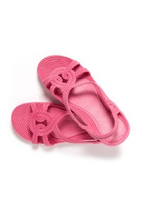 Sandalias de color rosa brillante con tiras texturizadas en forma de cuerda y suelas planas, dispuestas superpuestas sobre un fondo blanco.