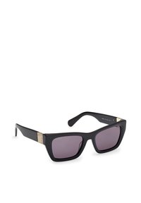 Gafas de sol negras con montura de plástico grueso, lentes de gradiente gris y detalles en dorado en las varillas. Forma angular con un diseño moderno.