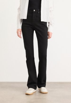 Black jeans with a slim fit, made from denim. Features five pockets and a front button closure. Worn with a black top and striped shirt.