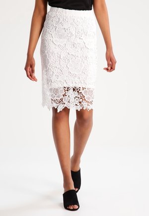 Hvid pencilnederdel i blonder med blomsterengel, der har en bølget kant. Bæres sammen med sorte åbne mule sandaler og en sort top.