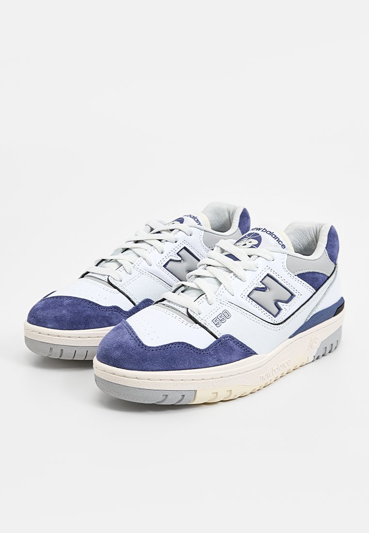 Baskets blanches et bleues ensuédées et en cuir. Présentent un logo "N" bien en vue, une languette rembourrée et une semelle en caoutchouc texturée.