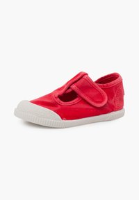 Chaussure rouge pour tout-petit avec semelle en caoutchouc blanche et embout, dotée d'une large bride en Velcro unique sur le dessus pour un maintien sécurisé.