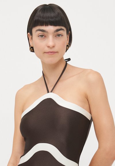 Braunes Halterkleid mit tailliertem Design, das an der Halslinie weiße Wellenverzierungen und eine glatte, glänzende Textur aufweist.