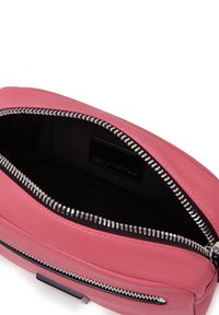 Borsa in pelle rosa con zip in cima, esterno texturizzato e fodera interna nera. Presenta una chiusura lampo in argento e un piccolo etichetta con il marchio.