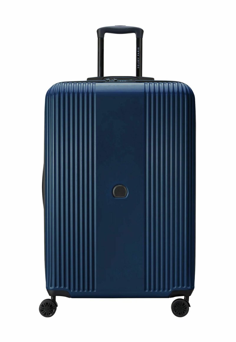 Valigia rigida blu navy con texture a righe verticali, manico nero retrattile e due ruote per la mobilità. Logo mostrato centralmente.