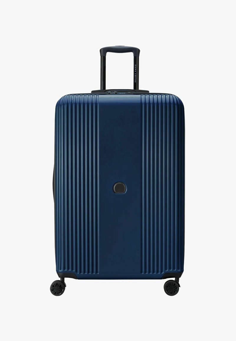 Valigia rigida blu navy con texture a righe verticali, manico nero retrattile e due ruote per la mobilità. Logo mostrato centralmente.