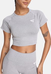 Szary crop top wykonany z elastycznej tkaniny z okrągłym dekoltem i krótkimi rękawami. Posiada białe logo z przodu. Subtelna tekstura.