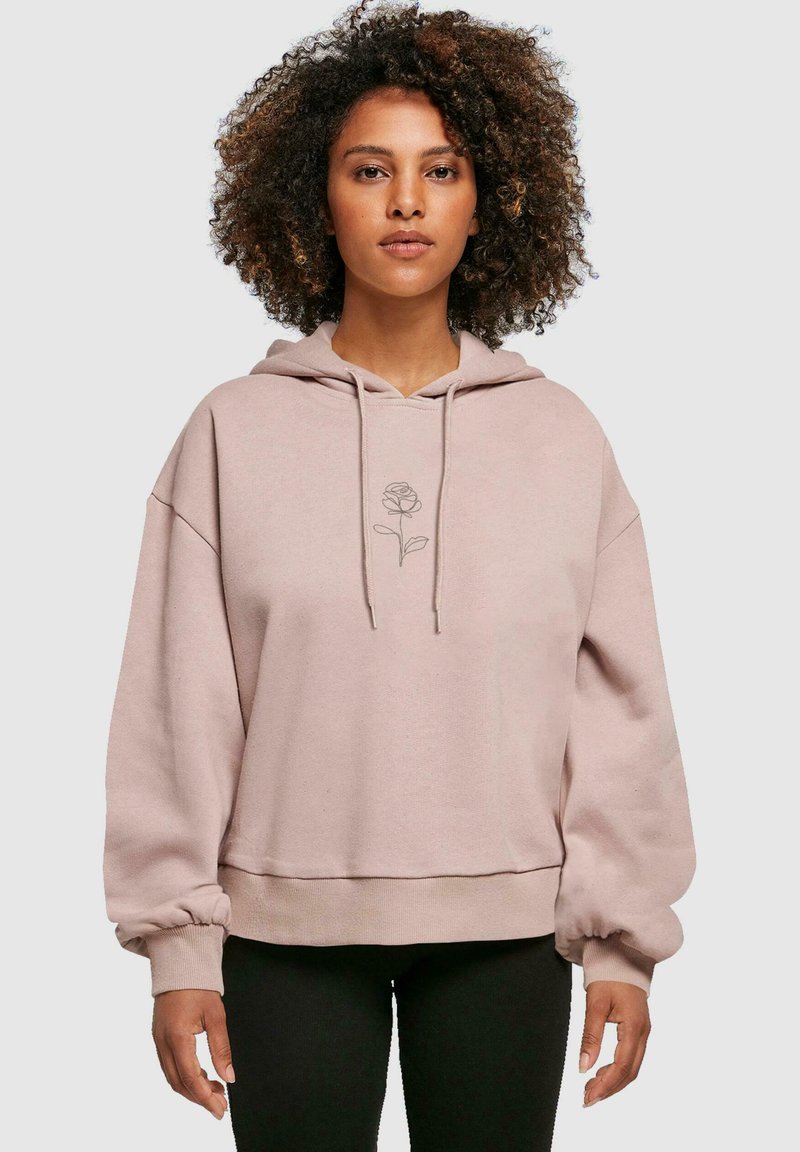 Sudadera de color rosa claro hecha de una tela suave, con un gráfico de una rosa en el centro, de corte oversized y con puños fruncidos para añadir textura.