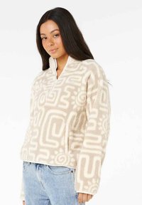 Fleece pullover i beige med teksturerede abstrakte mønstre, halvlange lynlås foran, lange ærmer og sidelommer. Blødt og let stof.