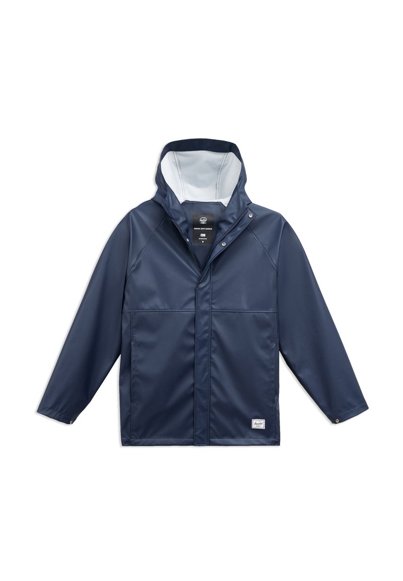 Laadukkaasti vedenpitävä tummansininen takki, jossa on huppu, etuosan napitus ja kaksi sivutaskua. Takissa on sileä pinta ja vaalea sisävuori, joka tuo kontrastia.