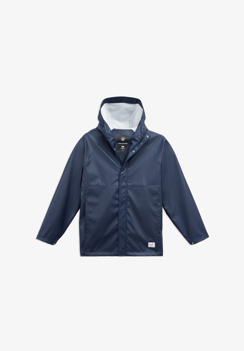 Laadukkaasti vedenpitävä tummansininen takki, jossa on huppu, etuosan napitus ja kaksi sivutaskua. Takissa on sileä pinta ja vaalea sisävuori, joka tuo kontrastia.