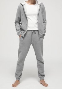 Grå sweatshirt och sweatpants-set i mjukt material. Huvtröja med dragsko, framfickor och elastiska muddar; avslappnad passform.