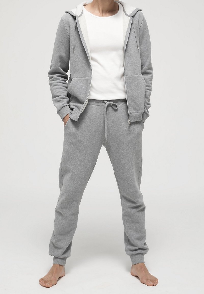 Grå sweatshirt och sweatpants-set i mjukt material. Huvtröja med dragsko, framfickor och elastiska muddar; avslappnad passform.