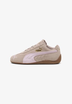 Beige suède Puma sneaker met roze streep, gouden Puma-logo, laag profiel, vetersluiting en bruine rubberen zool, afgebeeld vanaf de zijkant.
