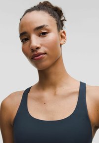 Satrastīgs sporta krekls tumšā jūras zilā krāsā, izgatavots no gludas auduma. Tam ir plati siksnas un apaļa kakla izgriezuma, izceļot ādas toni un plecu kontūras.