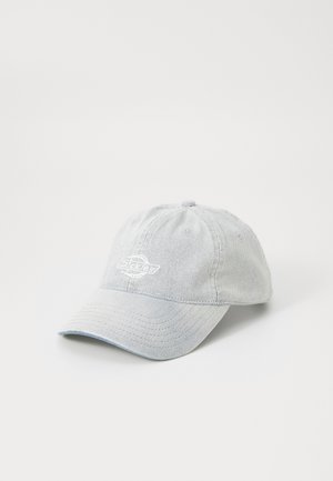 Casquette de baseball en denim bleu clair avec une visière courbée et un logo blanc brodé sur le panneau avant, présentée sur un fond blanc.