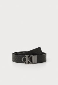 Zwarte leren riem met een gestructureerd patroon en een metalen gesp met een logo. De riem is glad en plat met een klassiek ontwerp.