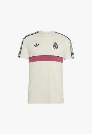 T-shirt de sport crème à manches courtes avec des bandes noires Adidas sur les épaules, une bande horizontale marron, logo Adidas sur la poitrine gauche et emblème du Real Madrid sur la poitrine droite.