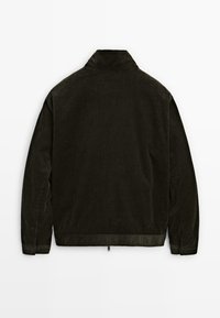 En mörkgrön kordflanorock med hög krage, långa ärmar, textilstruktur och ribbat mönster. Minimalistisk design utan synliga knäppningar.