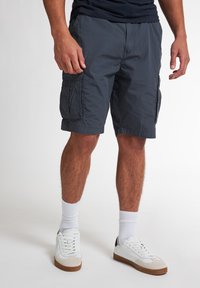 Mørkegrå cargo shorts lavet af letvægtsstof, med sidelommer og en afslappet pasform. Båret med hvide sneakers og ankelsokker.