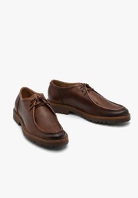 Brązowe skórzane buty z zapięciem na sznurówki, okrągłym noskiem, teksturowaną cholewką oraz grubą, solidną podeszwą z wyraźnymi rowkami.