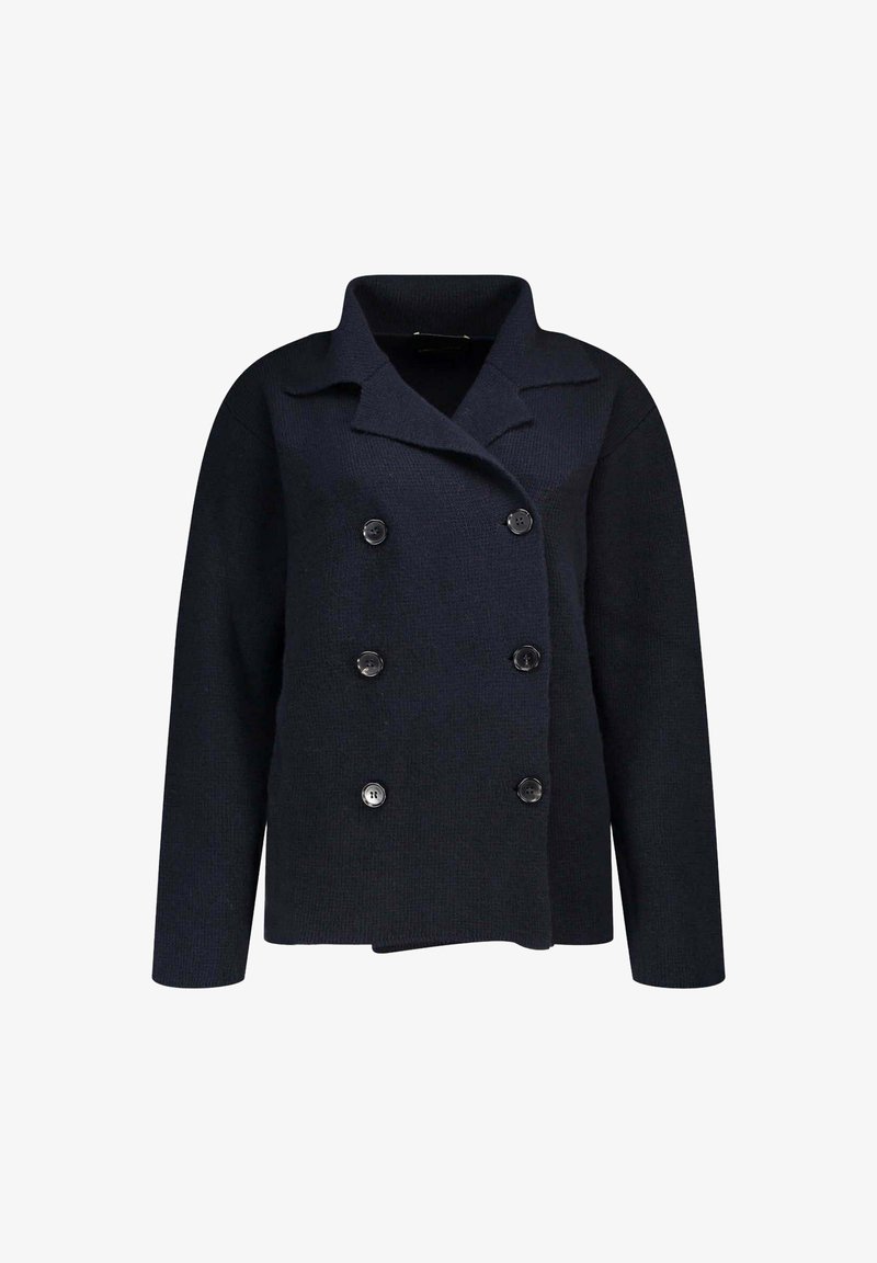Veste en tricot bleu marine à double boutonnage avec un col cranté, dotée de boutons noirs ronds et d'une silhouette arrondie. Texture douce.