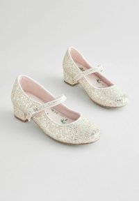 Glitzernde silberne Mary Jane-Schuhe mit runder Spitze, niedriger Absätze und einem Schnallenriemen. Das sanfte rosa Innenfutter hat ein Blumenmuster.