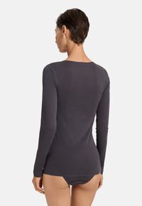 Dlouhý rukáv, tmavě šedý top vyrobený z měkkého materiálu. Má kulatý výstřih a přiléhavý střih, s minimálními švy.