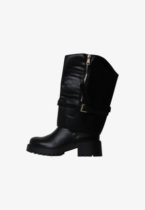 Botte en cuir noire mi-mollet avec talon épais, fermeture éclair latérale et bride décorative à boucle sur fond blanc.