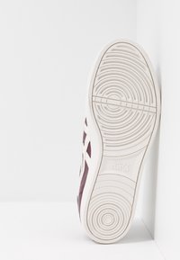 Sneaker Asics con punta sintetica color amaranto, suola in gomma bianca, motivo a battistrada circolare e logo impresso sulla suola.