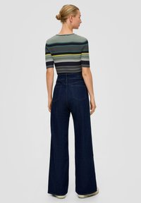 Gestreepte ribben top in groen, grijs en zwart met korte mouwen, gecombineerd met hoge taille flared jeans in donkerdenim. Getextureerd en aansluitend.