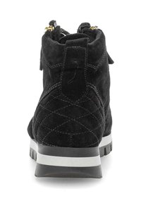 Bottines en daim noir avec un motif matelassé, dotées d'une semelle blanche et de détails en métal doré sur la fermeture éclair arrière.