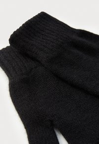Schwarze gestrickte Handschuhe mit einem gerippten Bündchen und strukturiertem Stoff, der eine glatte Oberfläche und eine enge Passform für Wärme bietet.