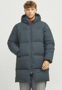 Padded hooded coat in dark grey, featuring a zip front, side pockets, and a long silhouette. Smooth texture with a quilted design.