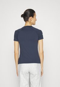 Navy blauwe getailleerde t-shirt met korte raglanmouwen, een gladde textuur en een ronde halslijn, gedragen met gestreepte witte broek.