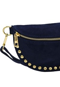 Sac en daim bleu marine avec une forme incurvée, fermeture éclair et quincaillerie dorées, et clous décoratifs dorés le long du bord. Dispose d'une petite sangle pour le poignet.
